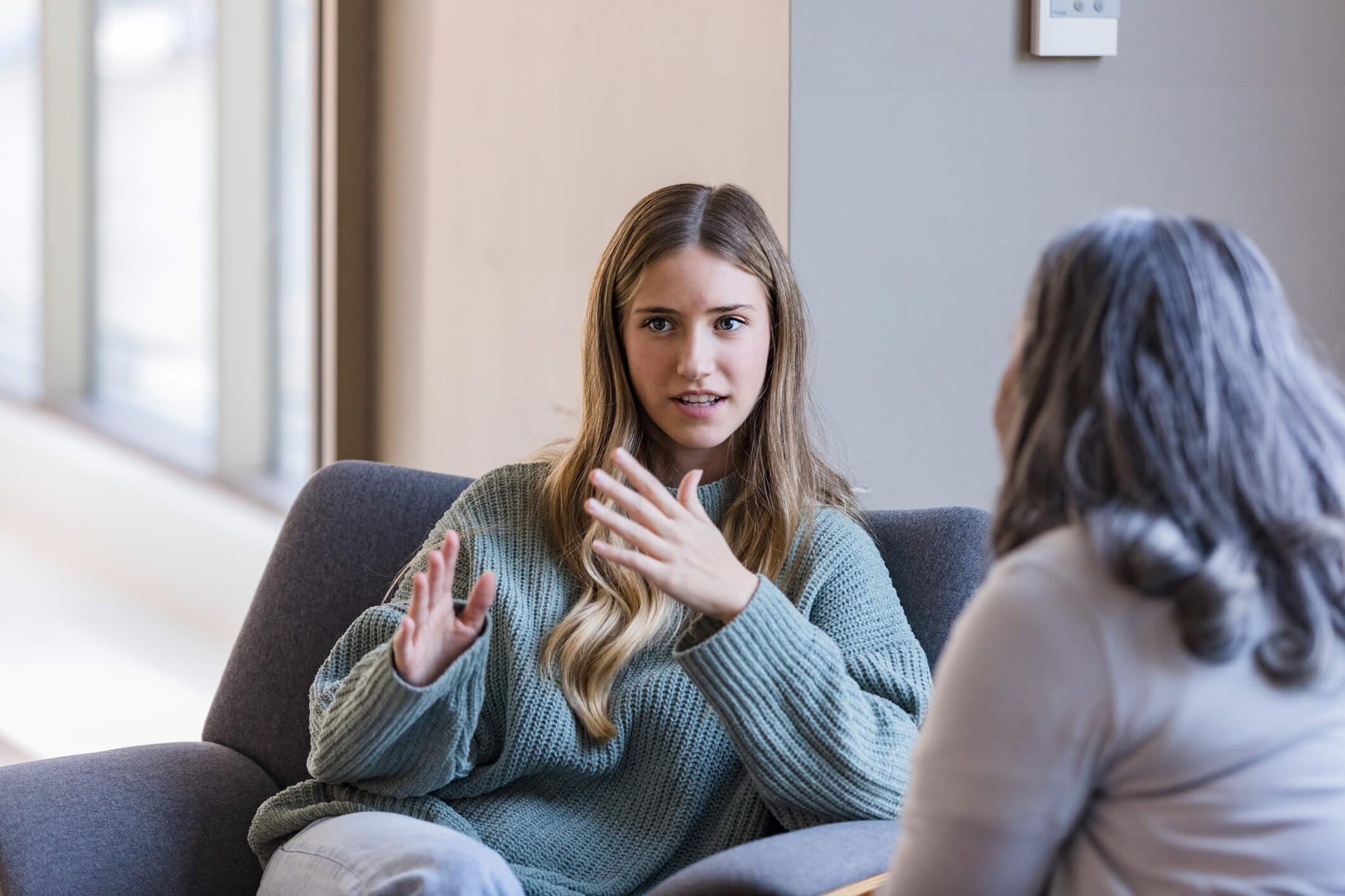 Woman in a green sweater talking about mental disorders with her counterpart.