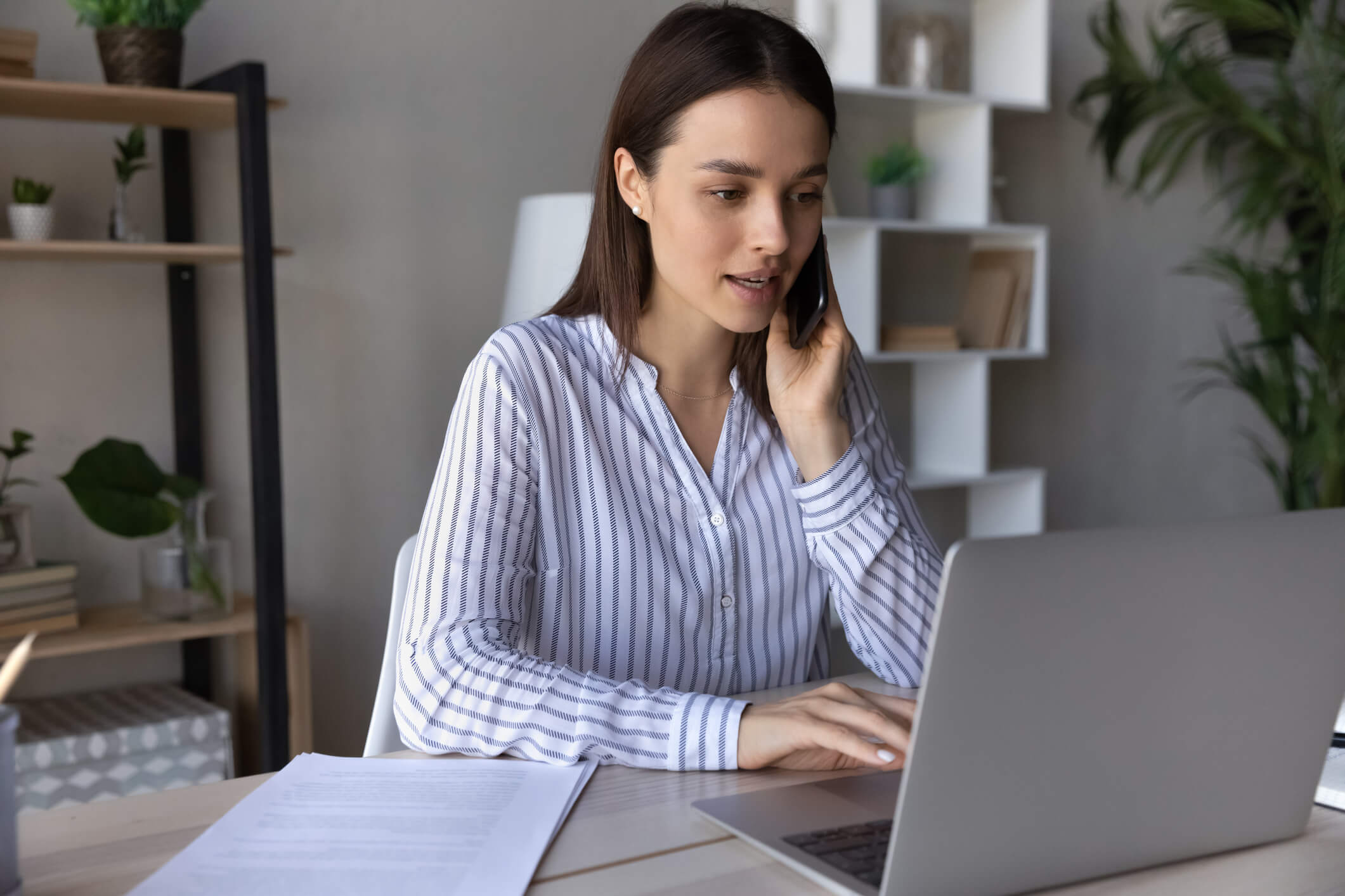 Woman sitting at a desk on the phone making an appointment with her mental health provider.