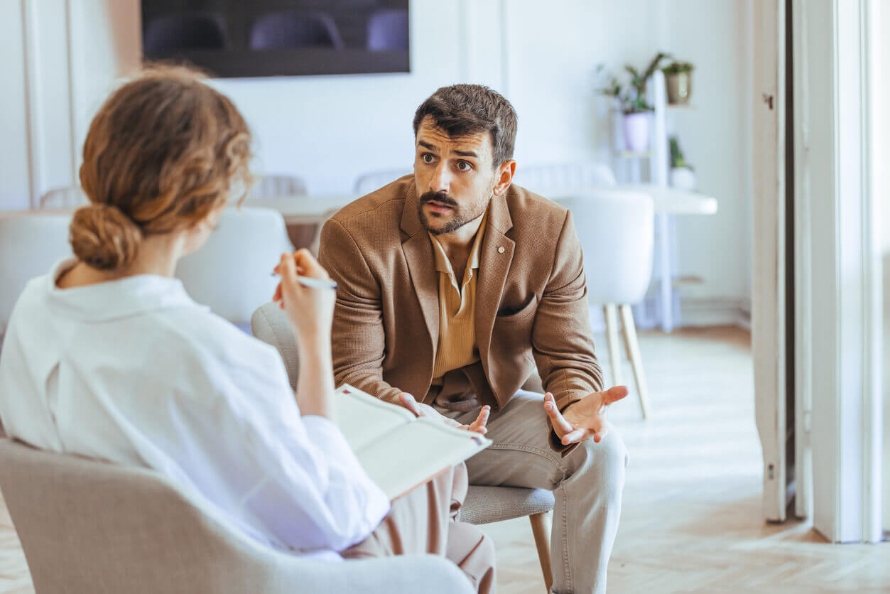 A man is engaged in conversation during a professional life coaching therapy session.