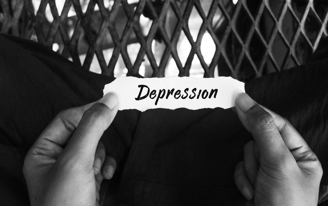 Top view of hand holding torn paper with depression message on black and white background.