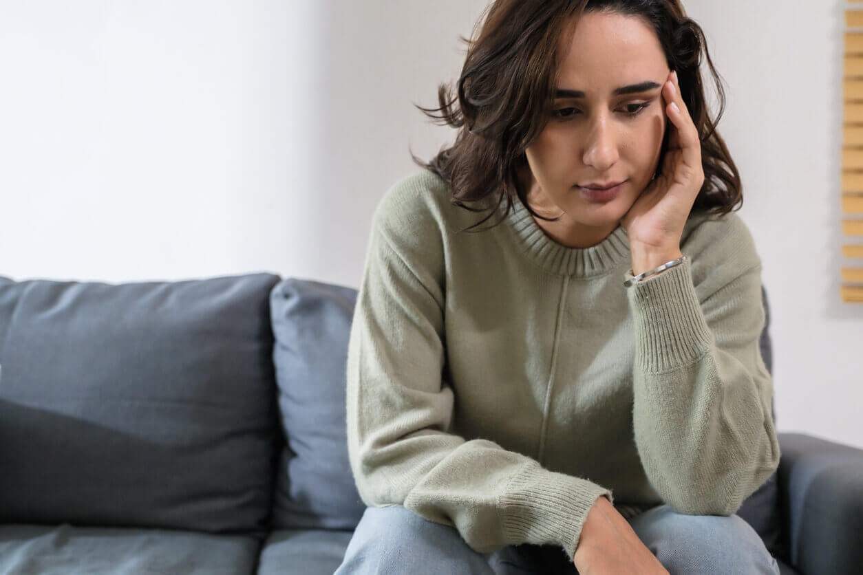 Sad anxious woman feeling stress and depression while sitting alone on sofa.