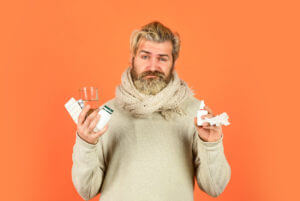A man suffering from depression is holding several medications and Antidepressant Nasal Spray.